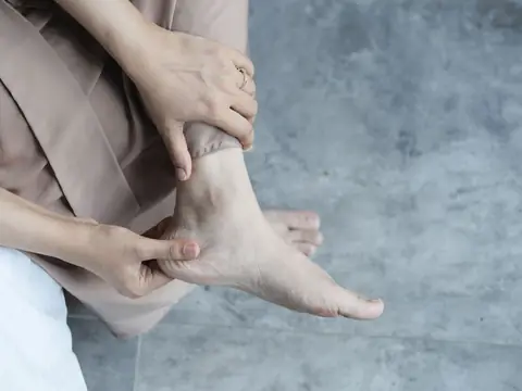A person holding the heel and ankle of a bare foot