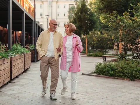 A senior couple walking together through a leafy city park