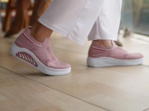 A person walking indoors in soft pink knit walking shoes